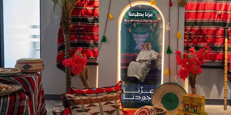 Event setup featuring a banner with Saudi National Day branding and traditional decor.